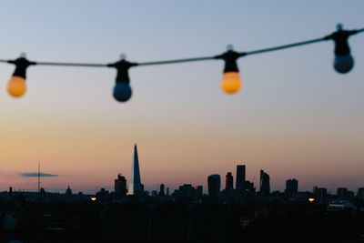 Light bulbs hanging against shard london bridge during sunset