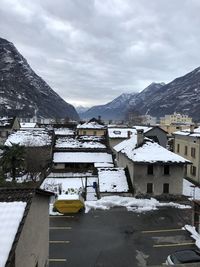 Snow covered buildings by mountain against sky