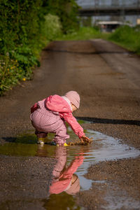 A small child is playing in a rain puddle