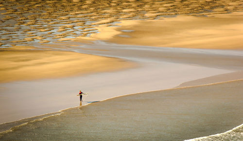 Woman carrying surfboard on shore at beach