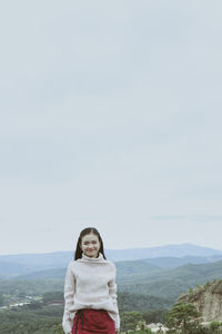 Portrait of woman standing against sky