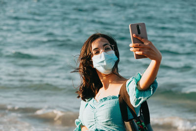 Young woman using mobile phone in sea