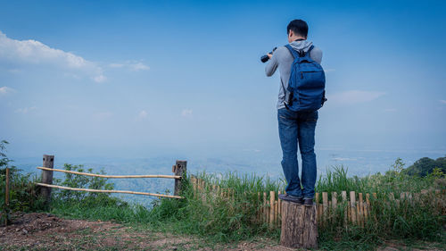 Man standing by plants against blue sky