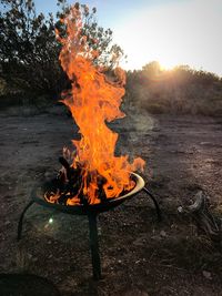 Close-up of bonfire on field against sky at sunset