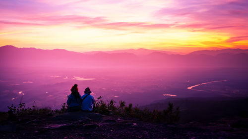 Rear view of woman walking on mountain against sky during sunset