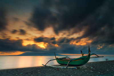 Ship moored on sea against dramatic sky