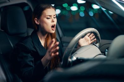 Angry young woman sitting in car