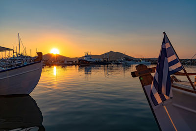 Sailboats moored in sea against sky during sunset