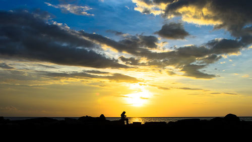 Silhouette people standing on beach against sky during sunset