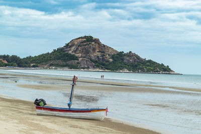 Boat moored at beach against sky