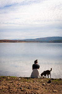 Woman and brown dog near the lake on a beautiful landscape view