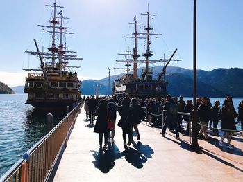 People at harbor at sea against sky