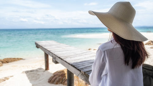 Rear view of woman standing at beach against sky