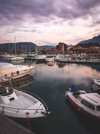 Boats moored in harbor at sunset