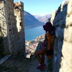 Side view of woman looking at buildings against mountain