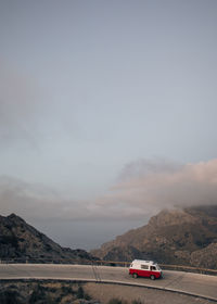 Van moving on road overlooking mountains against sky