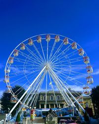 Low angle view of ferris wheel against blue sky