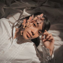 High angle portrait of teenage girl with decorations lying on bed