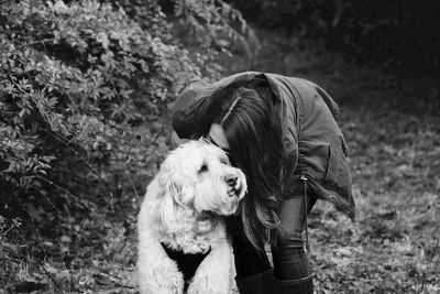 Woman kissing dog while standing on field