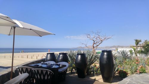 Chairs on beach against clear sky