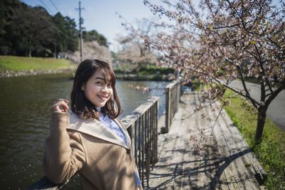 Portrait of smiling woman standing against trees