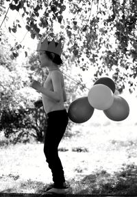 Rear view of boy holding umbrella against trees