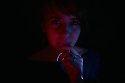 Close-up portrait of young woman over black background