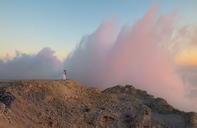 Rear view of woman standing on mountain against sky