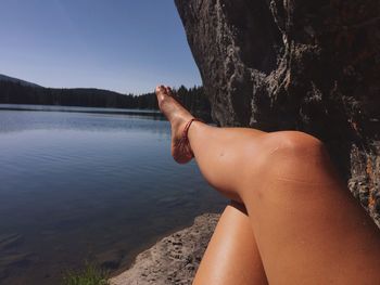 Low section of woman on lake against sky