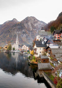 Lake by buildings in town against sky