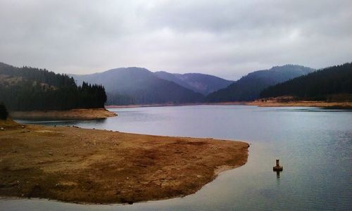 Scenic view of lake by mountains against sky