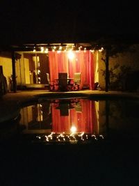 Illuminated building reflecting in water