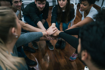 High angle view of business persons stacking hands together in office