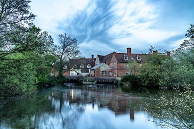 Houses by lake and buildings against sky