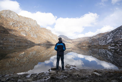Rear view of man standing on mountain against sky