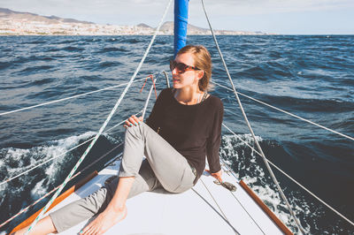 Smiling young woman sitting in boat on sea