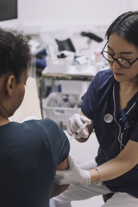 Female gynecologist wearing eyeglasses injecting patient during ivf in medical clinic