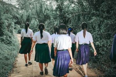 Rear view of people walking on street amidst trees