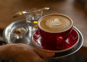 Midsection of person holding coffee cup on table