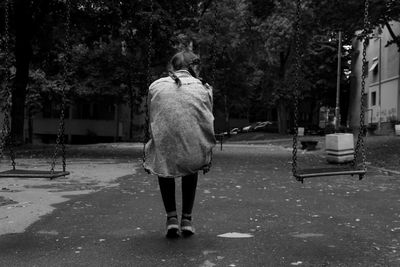 Rear view of woman walking on road along trees