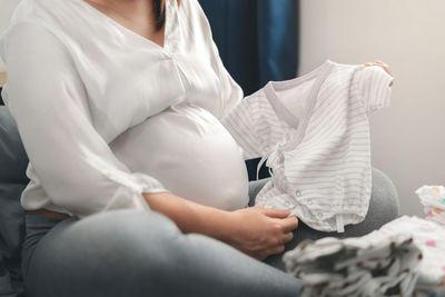 Low section of woman sitting on bed at home