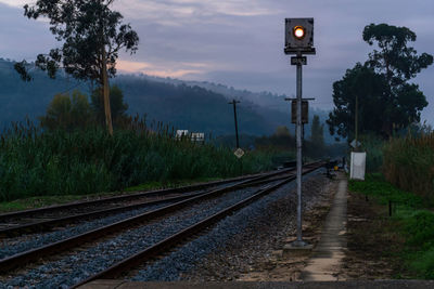 Landscape with railway semaphore, eucalyptus tree and railway tracks against hills in fog 