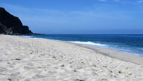 Scenic view of beach against clear blue sky