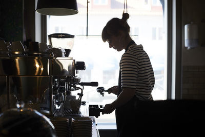 Female barista using coffee filter at cafe