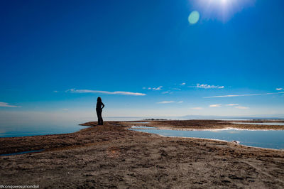 Man standing on beach against blue sky