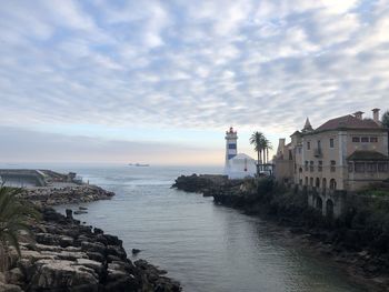 Lighthouse by sea against sky