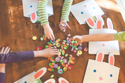 Cropped image of children holding easter candies on wooden floor