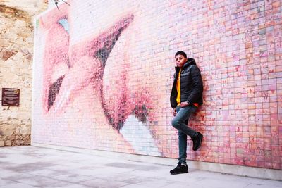 Full length of young man standing against wall