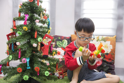 Boy playing with toy by christmas tree at home