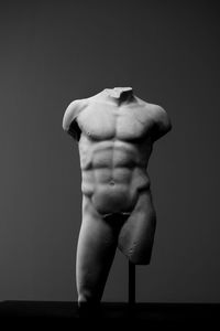 Midsection of shirtless man against black background